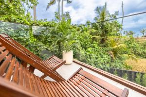 two wooden benches sitting on a balcony with a plant at Bale Marva, Gianyar - Modern Tropical Hideaway near Ubud & Bali Safari Park in Lebih