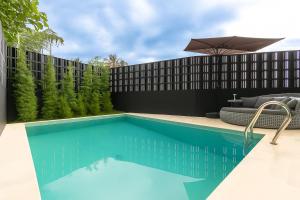 a swimming pool with an umbrella next to a building at Bale Marva, Gianyar - Modern Tropical Hideaway near Ubud & Bali Safari Park in Lebih