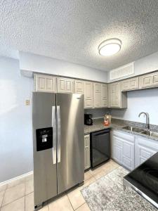 a kitchen with a stainless steel refrigerator and white cabinets at 1BD Condo HWY161-183 DFW South Irving - I67 in Sowers