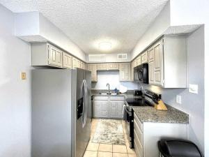 a kitchen with white cabinets and a stainless steel refrigerator at 1BD Condo HWY161-183 DFW South Irving - I67 in Sowers