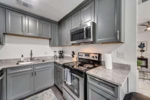 eine Küche mit Geräten aus Edelstahl und grauen Schränken in der Unterkunft 1BD Condo HWY161-183 DFW South Irving I65 in Sowers