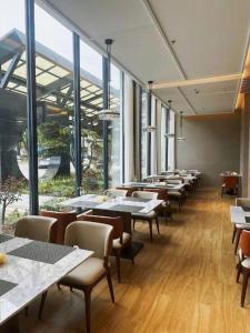 a restaurant with tables and chairs and large windows at Zhangjiagang Jiangnan Garden Hotel in Xiwujieqiao