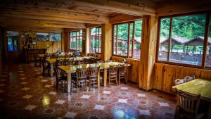 a restaurant with wooden tables and chairs and windows at Isikli Kale Hotel in Çaykara