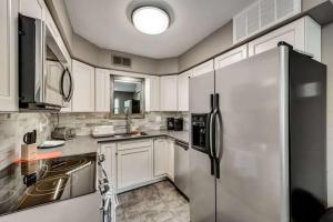 a kitchen with white cabinets and a refrigerator at 1BD Condo HWY161-183 DFW South Irving - I63 in Sowers