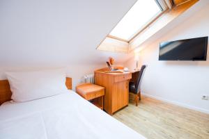 Un dormitorio con una cama, un escritorio y un televisor. en Hotel Admiral am Zoo, en Frankfurt