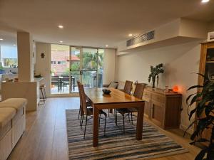 a kitchen and dining room with a wooden table and chairs at South Cronulla Liandys in Cronulla