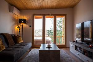 a living room with a couch and a flat screen tv at Nature&Chill Treehouses in Sopron