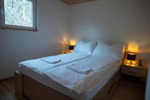 a bed in a bedroom with two lights on two tables at Nature&Chill Treehouses in Sopron