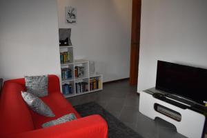 a living room with a red couch and a flat screen tv at AL30 Studios in Viverone