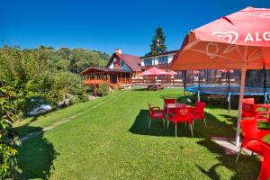 een groep rode stoelen en een parasol op een gazon bij Penzion u Kukačků in Horní Planá