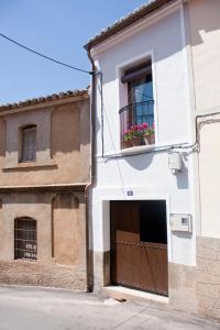 a white building with a brown door and a window at Casa de la Panadería in Los Navalucillos