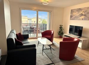 een woonkamer met een bank, stoelen en een televisie bij Deux pas du lac & Centre de Montreux in Veytaux