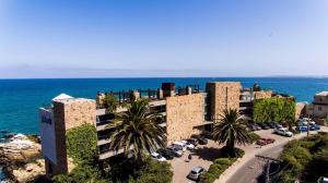 a building with cars parked in a parking lot next to the ocean at Radisson Blu Acqua Hotel & Spa Concon in Concón