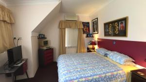 Aarn House B&B Airport Accommodation في بيرث: غرفة نوم فيها سرير وتلفزيون