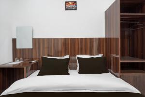 バラナシにあるSuper Collection O Banaras Railway Junction Formerly Varanasi Suitesのベッドルーム1室(大型ベッド1台、木製ヘッドボード付)