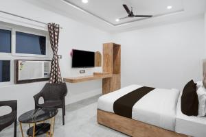 バラナシにあるSuper Collection O Banaras Railway Junction Formerly Varanasi Suitesのベッドとテレビと椅子のある寝室