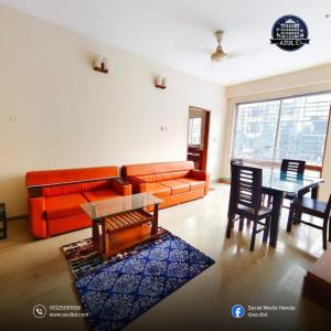 a living room with an orange couch and a table at Azul-Fully Furnished Modern Apartment in Bāiljuri
