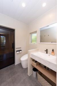 a white bathroom with a sink and a toilet at Hakuba Mitsuki Chalet in Hakuba +20 photos