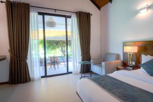a bedroom with a bed and a sliding glass door at Uppuveli Beach by DSK in Trincomalee