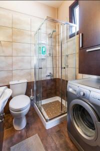 a bathroom with a shower and a toilet and a washing machine at Near the beach Aparment with garden in Pervolia +49 photos