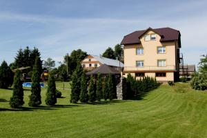 een groot huis met een rij bomen bij Agroturystyka nad Jeziorem Gaładuś in Dusznica