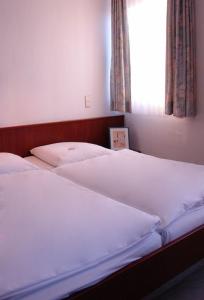 two white beds in a bedroom with a window at Hotel Filoxenia in Stuttgart