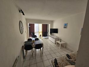 ein Wohnzimmer mit Tisch und Stühlen und einem Fernseher in der Unterkunft T2 CARRY LE ROUET CENTRE VILLE PROCHE DE LA MER in Carry-le-Rouet