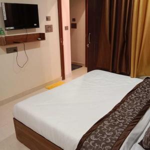 a bedroom with a bed and a flat screen tv at Hotel O The Honey Guest House in Haldwāni