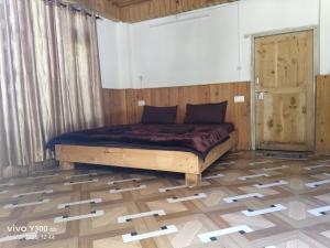 een slaapkamer met een bed en een houten vloer bij Shangarh JC Snow Valley in Shangarh +6 foto's