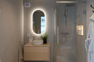 een badkamer met wastafel en douche met spiegel bij Hideaway Herdla luxurious cabins 15 m above the sea in Herlø +12 foto's