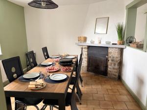 Maison pittoresque et cozy في Bonnat: غرفة طعام مع طاولة ومدفأة