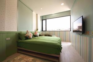 1 dormitorio con cama verde y ventana grande en 宜蘭羅東迷彩民宿-大吉迷彩 en Luodong