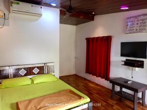 a bedroom with a green bed and a red curtain at River Garden Guest House in Jambhulpāda
