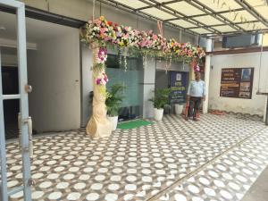 Um homem em pé em um prédio com um arco de flores. em Hotel Vista Haven em Patna