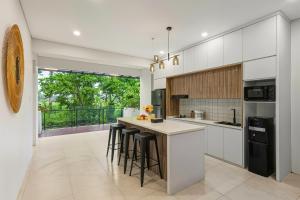 une cuisine avec des placards blancs et un îlot avec des tabourets de bar dans l'établissement JK Bhavana Villas, à Ngemplak