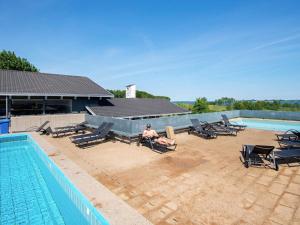 a man sitting in a chair next to a swimming pool at 6 person holiday home in Aabenraa in Aabenraa