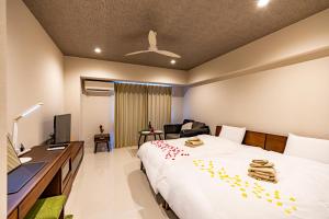 een slaapkamer met een bed en een bureau met een computer bij 真栄田岬グランブルー 104 in Onna