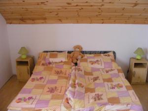 a teddy bear sitting on top of a bed at Tünde Vendégház in Bernecebaráti