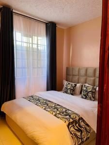 a bedroom with a large bed with a window at Fibi Embu Apartments in Embu