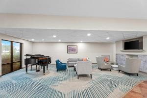 a waiting room with a piano and chairs at Comfort Suites Gothenburg South in Gothenburg