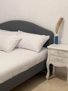 a bed with a black headboard and a white night stand at Palmera by LOREN VILLAGE in Neve Zohar