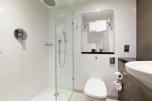 a bathroom with a shower and a toilet and a sink at Thistle London Piccadilly in London