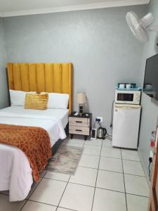 a small bedroom with a bed and a microwave at Ogans guest villa 20 Johan Meyer St, Linmeyer, Johannesburg in Johannesburg