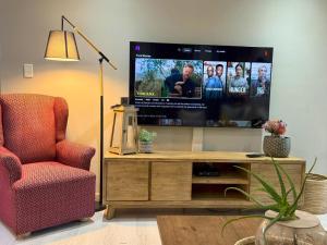 a living room with a flat screen tv and a chair at 20 At Jeanette in Ludwigsdorf