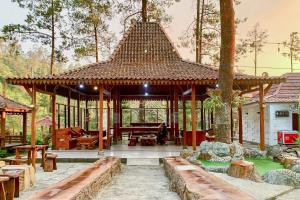 a pavilion with a table and chairs in a garden at Embun Lawu Cottage Tawangmangu in Sarangan