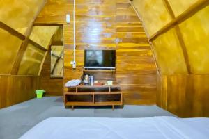 a room with a bed and a tv in a wooden wall at Embun Lawu Cottage Tawangmangu in Sarangan