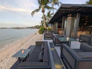 ein Restaurant am Strand mit Tischen und Stühlen in der Unterkunft Transit Samui Resort in Koh Samui  + 42 Fotos