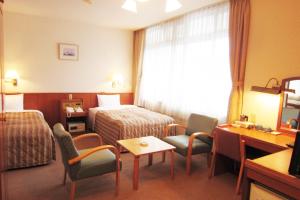 a hotel room with a bed and a table and chairs at Hotel Axia Kushikino in Ichikikushikino