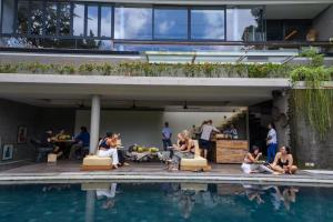 a group of people sitting next to a swimming pool at Yara Wellness in Munggu