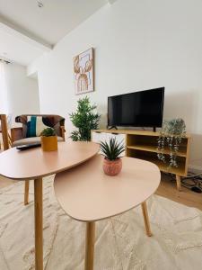 two tables in a living room with a tv at Charmant Appartement Rénové l 2 chambres in Réalmont